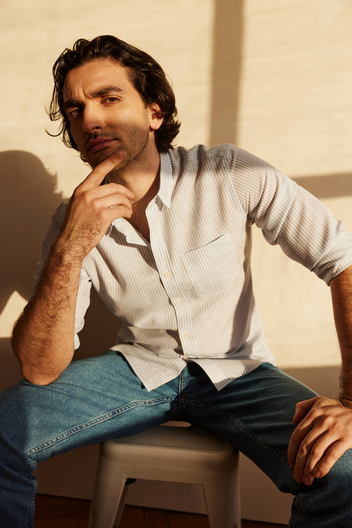 man wears a merino wool linen shirt from Wolk with chest pocket and light blue bengal stripe with white buttons