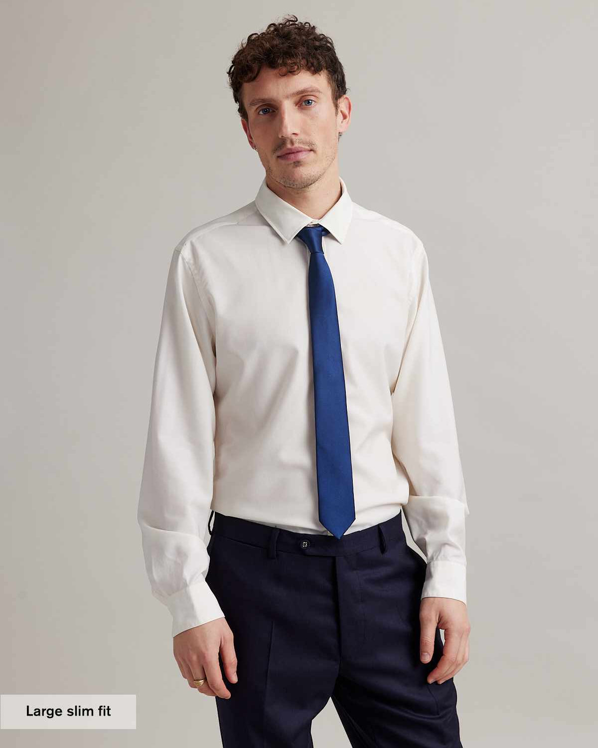 Man wears a white merino formal shirt with navy tie