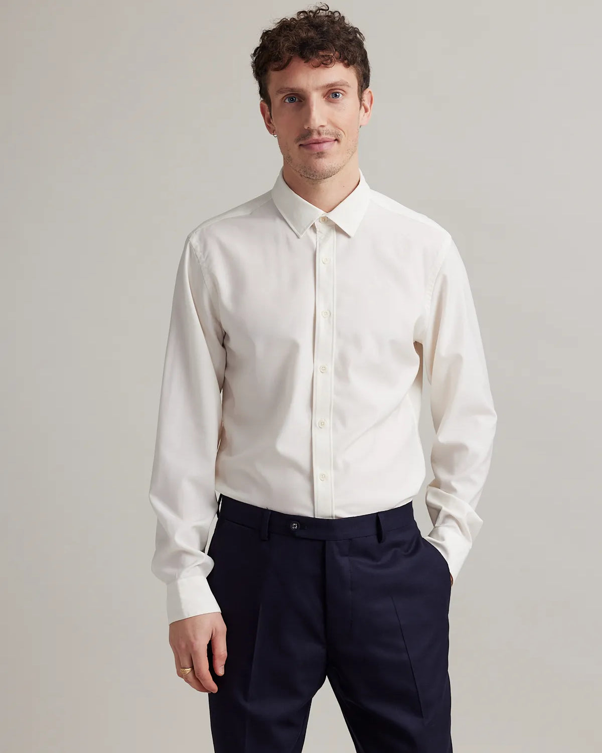 Front view of a man wearing a white merino wool dress shirt on a navy trousers.