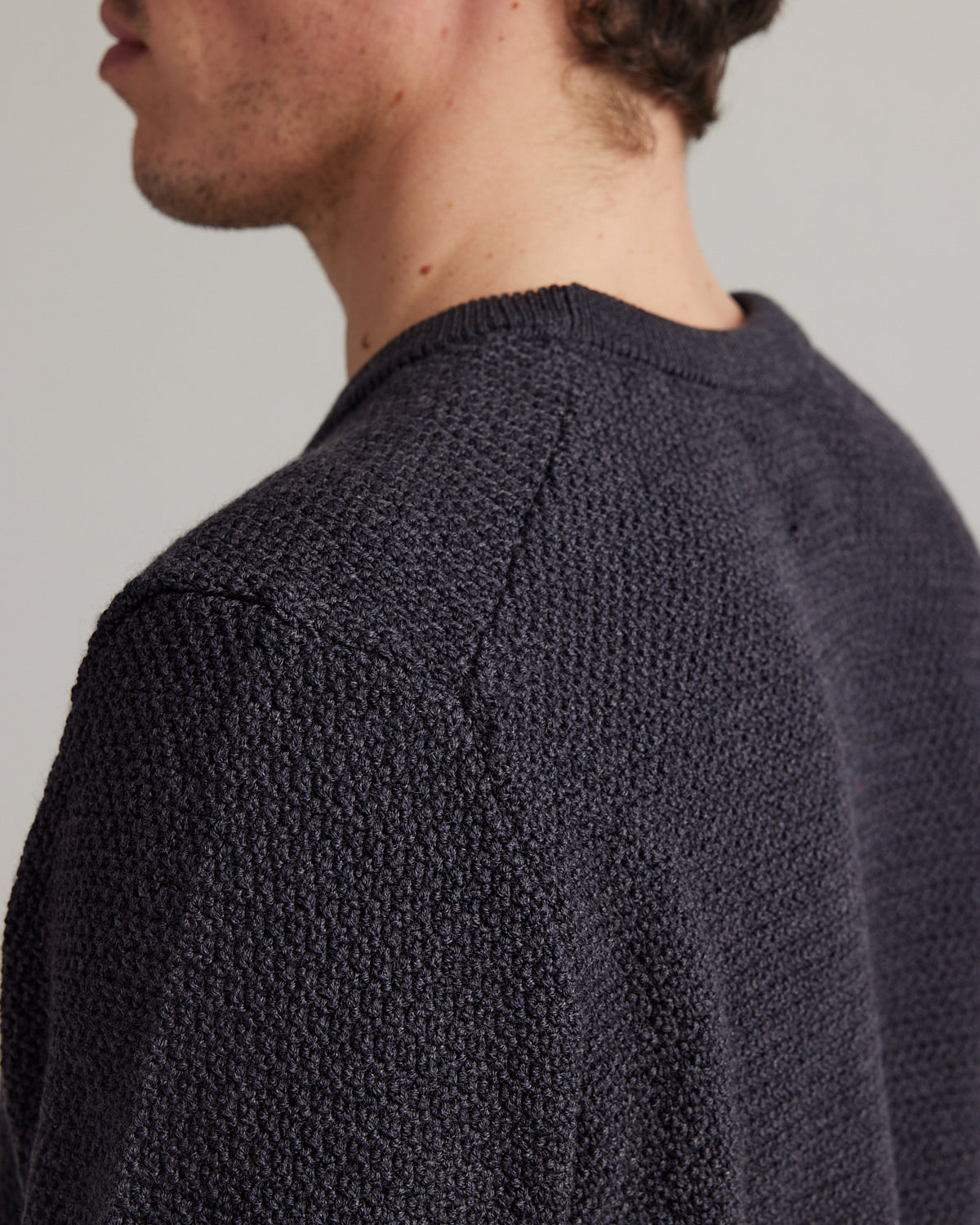 backside seam of merino wool sweater in rice knit structure and anthracite dark grey color