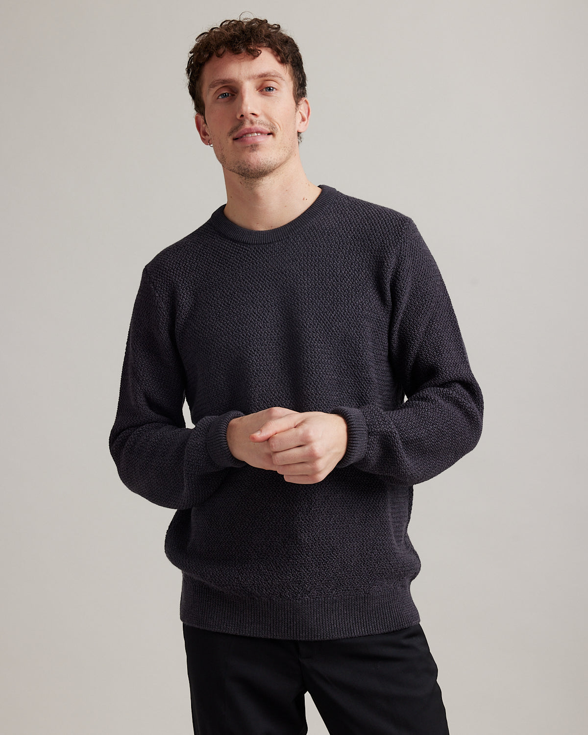 Man wearing a merino wool sweater in anthracite dark grey in rice knit stitch