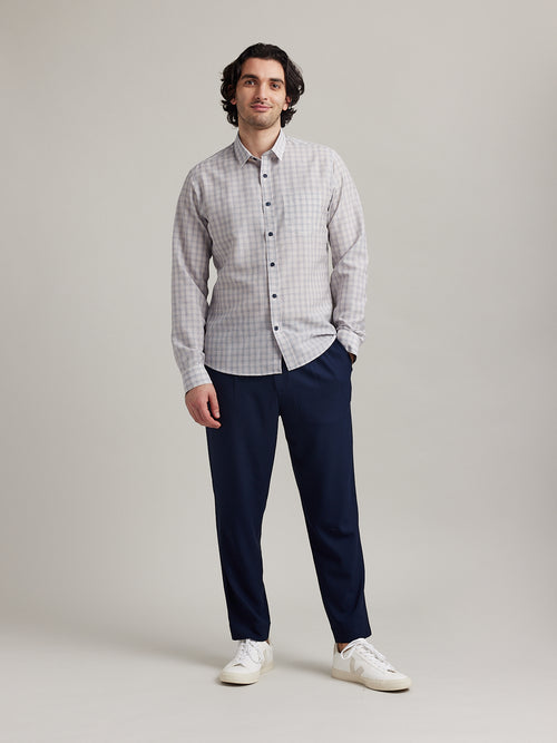 Man wears a linen merino shirt in white color with navy red line graph and navy buttons and long sleeves on navy pants