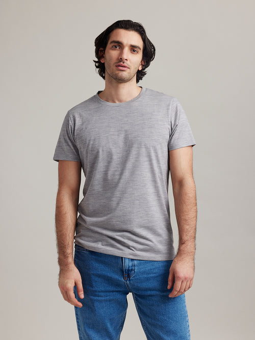 Man wears light grey melange merino wool T-shirt with crew neck and short sleeves from Wolk