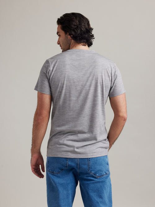 Back view of a male model wearing a light grey merino wool T-shirt from the Wolk brand.