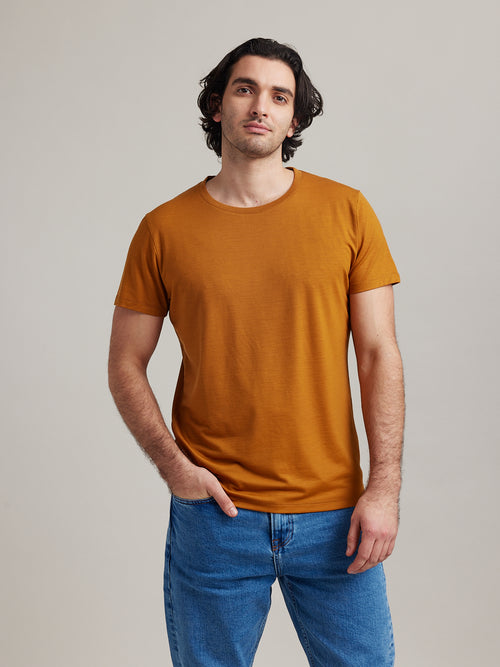 Man wears a merino wool T-shirt from Wolk in ochre color, crew neck and short sleeves.