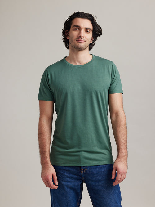 man wears a pine green merino wool T-shirt with short sleeves and crew neck