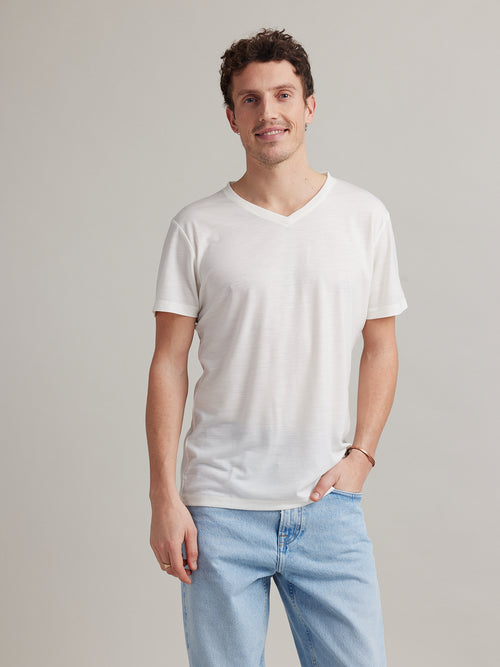 Man wears a white merino wool and nylon blend T-shirt with Vneck and short sleeves from Wolk