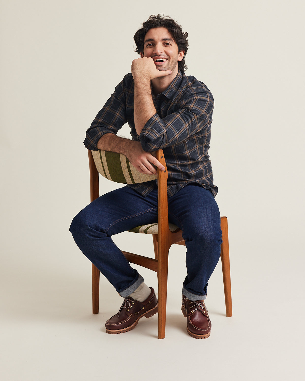 Man wears a merino wool flannel shirt with grey brown checked plaid on a dark jeans with boat shoes