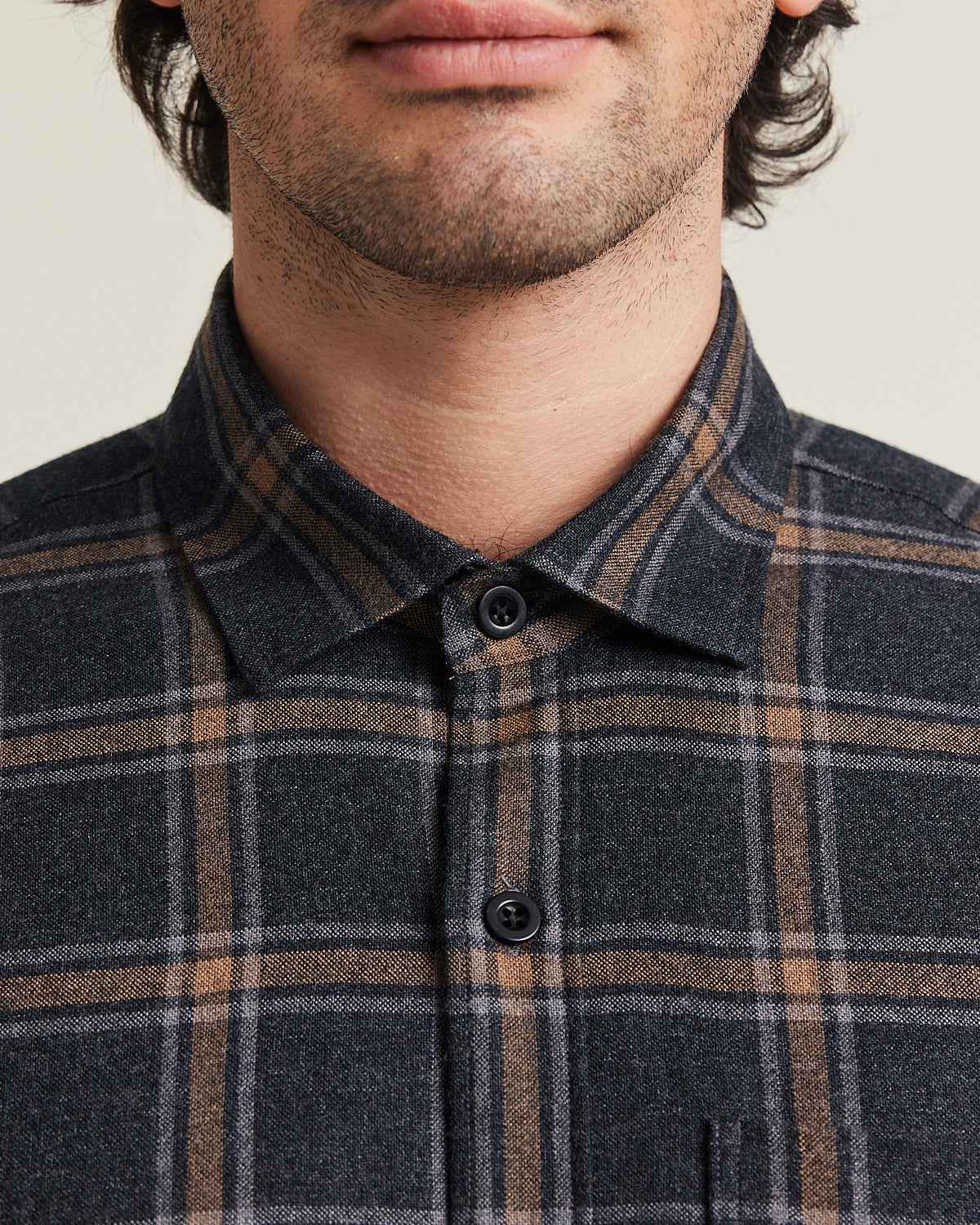 Close up of man wearing a merino wool shirt from Wolk with corozo buttons in grey brown plaid pattern