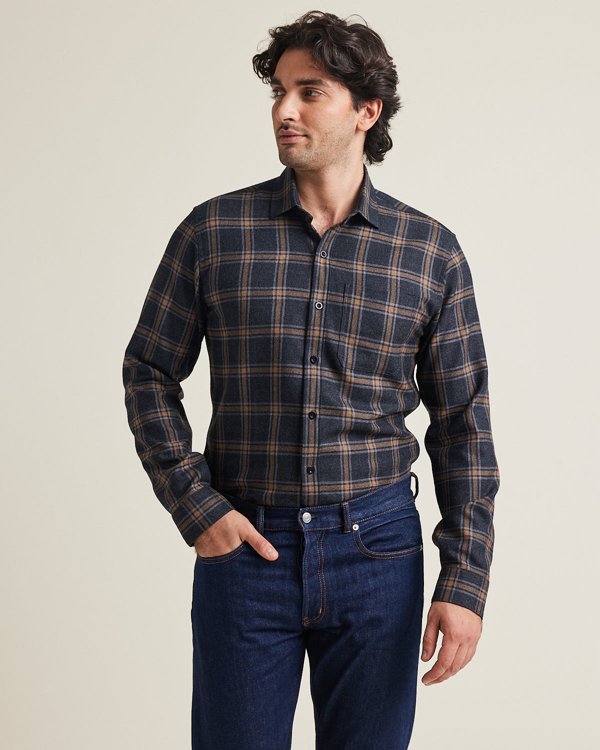 Man wears a merino wool flannel shirt from Wolk in grey brown plaid pattern with chest pocket