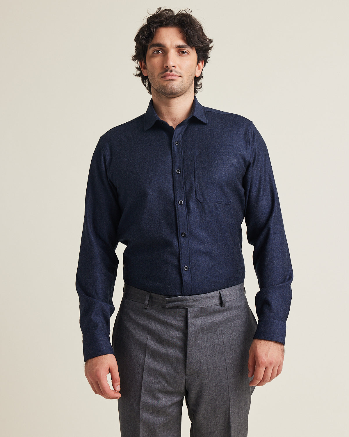 Man wears a merino flannel shirt in navy color with chest pocket on grey trousers