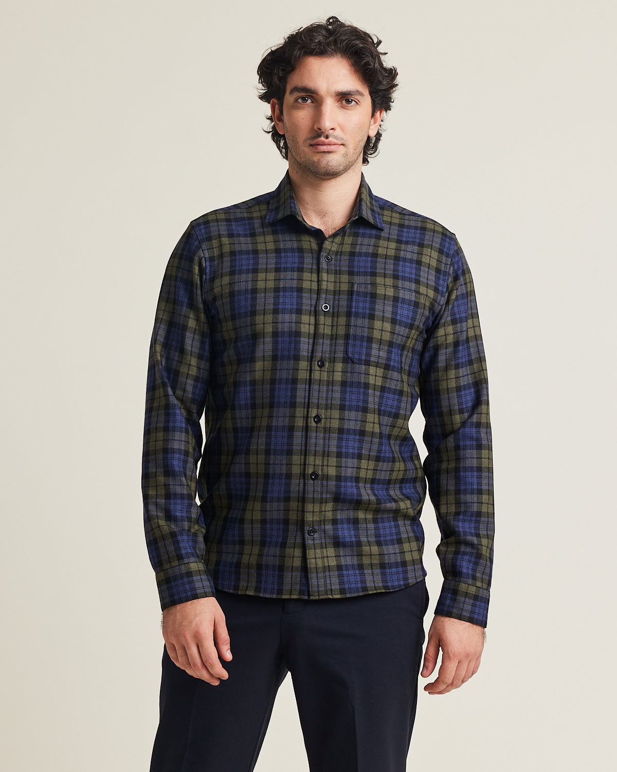 Man wears merino wool flannel shirt in blue green check pattern with chest pocket