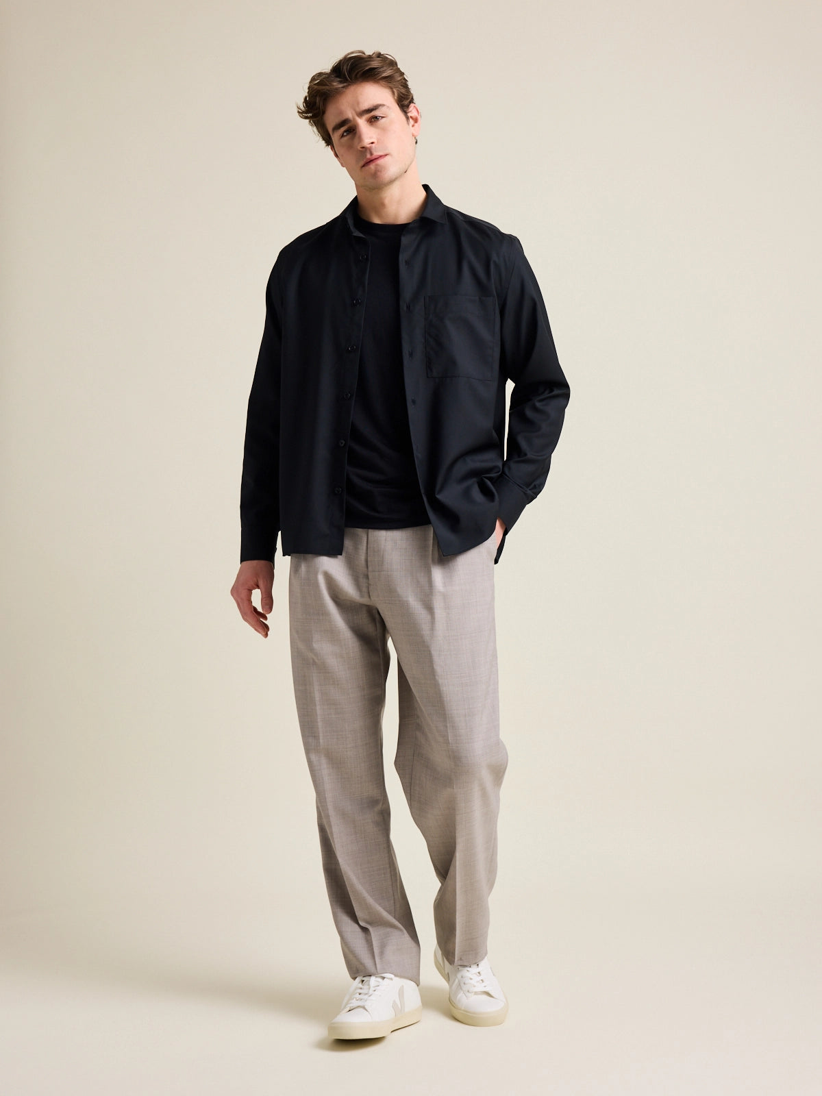 Man shows merino wool shirt from Wolk in black color on taupe wide fitted trousers.