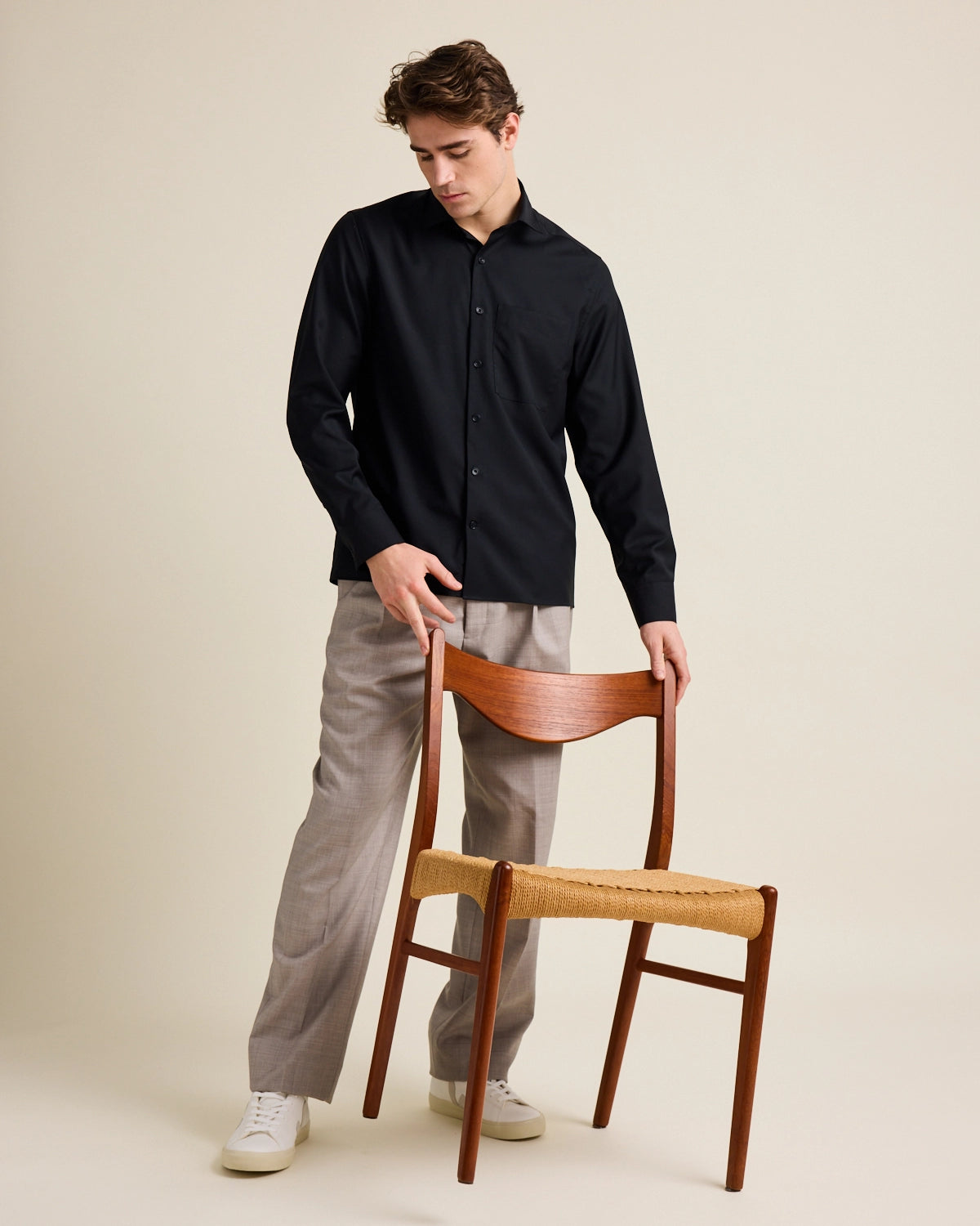 Man holds a vintage chair from Meteor Gallery. He wears a black wide boxy fit merino wool shirt from Wolk.
