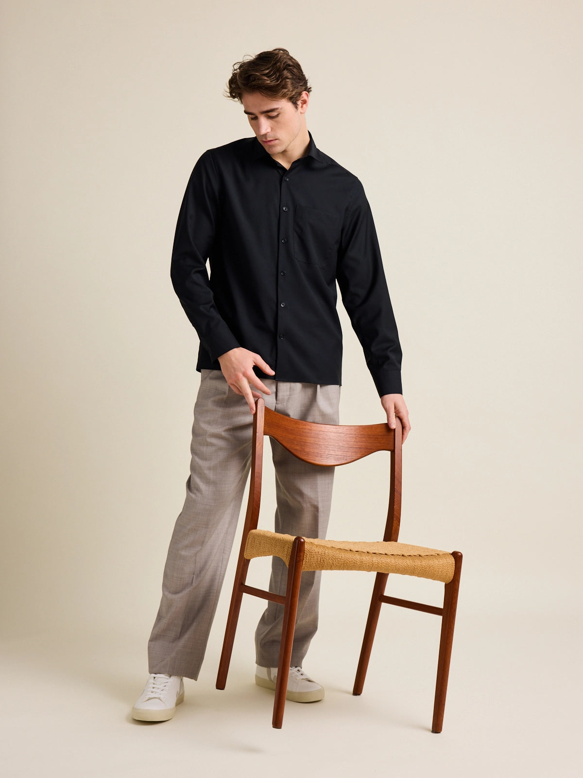 Man holds a vintage chair from Meteor Gallery. He wears a black wide boxy fit merino wool shirt from Wolk.