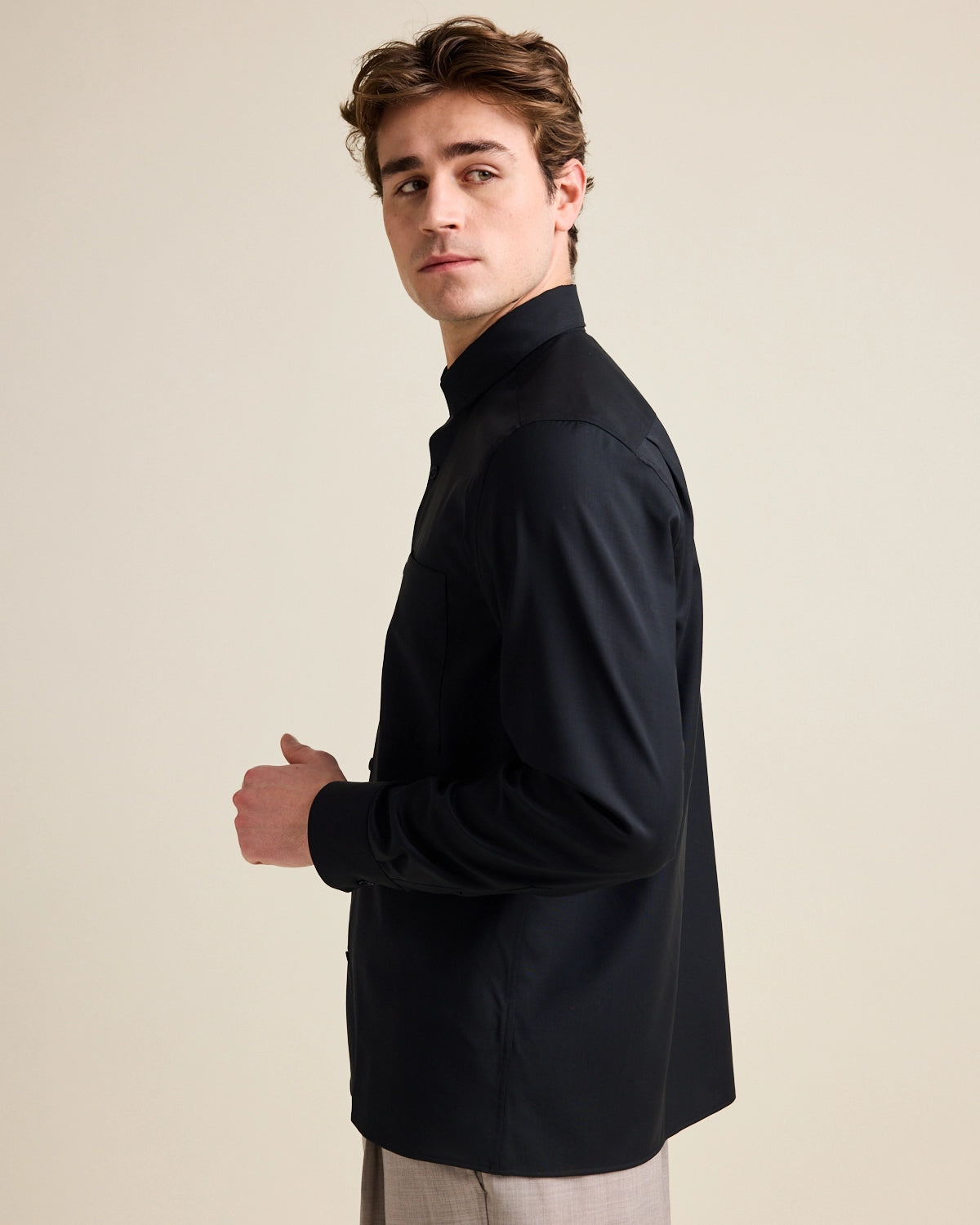 Man shows side of merino wool shirt with straight hem in black color.
