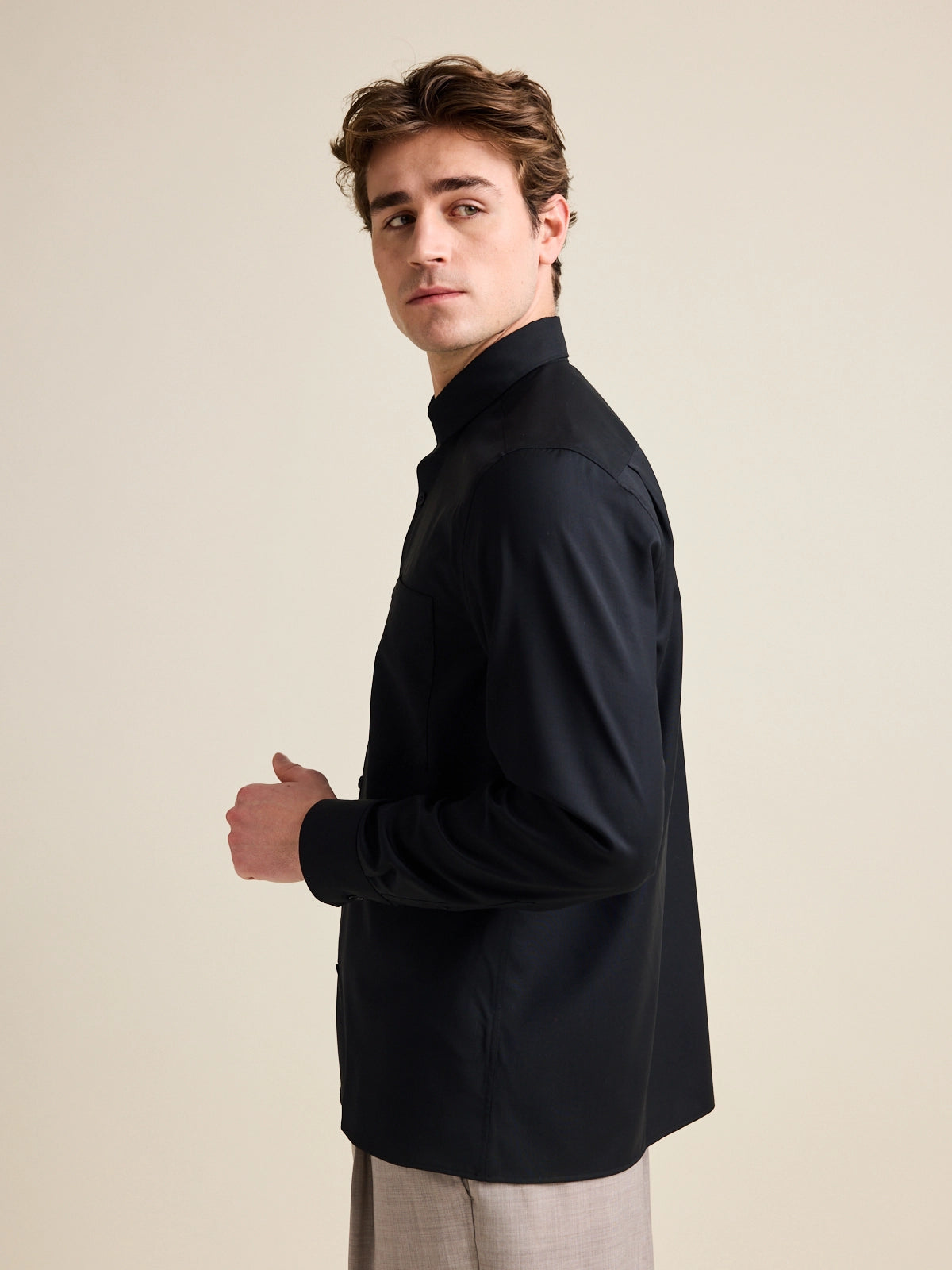 Man shows side of merino wool shirt with straight hem in black color.