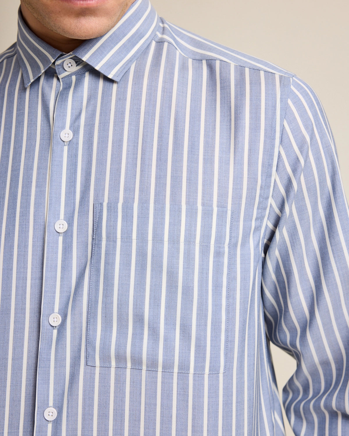 Detail of the chest pocket on a merino wool shirt for men. The merino wool shirt has a striped pattern in navy and white stripe.