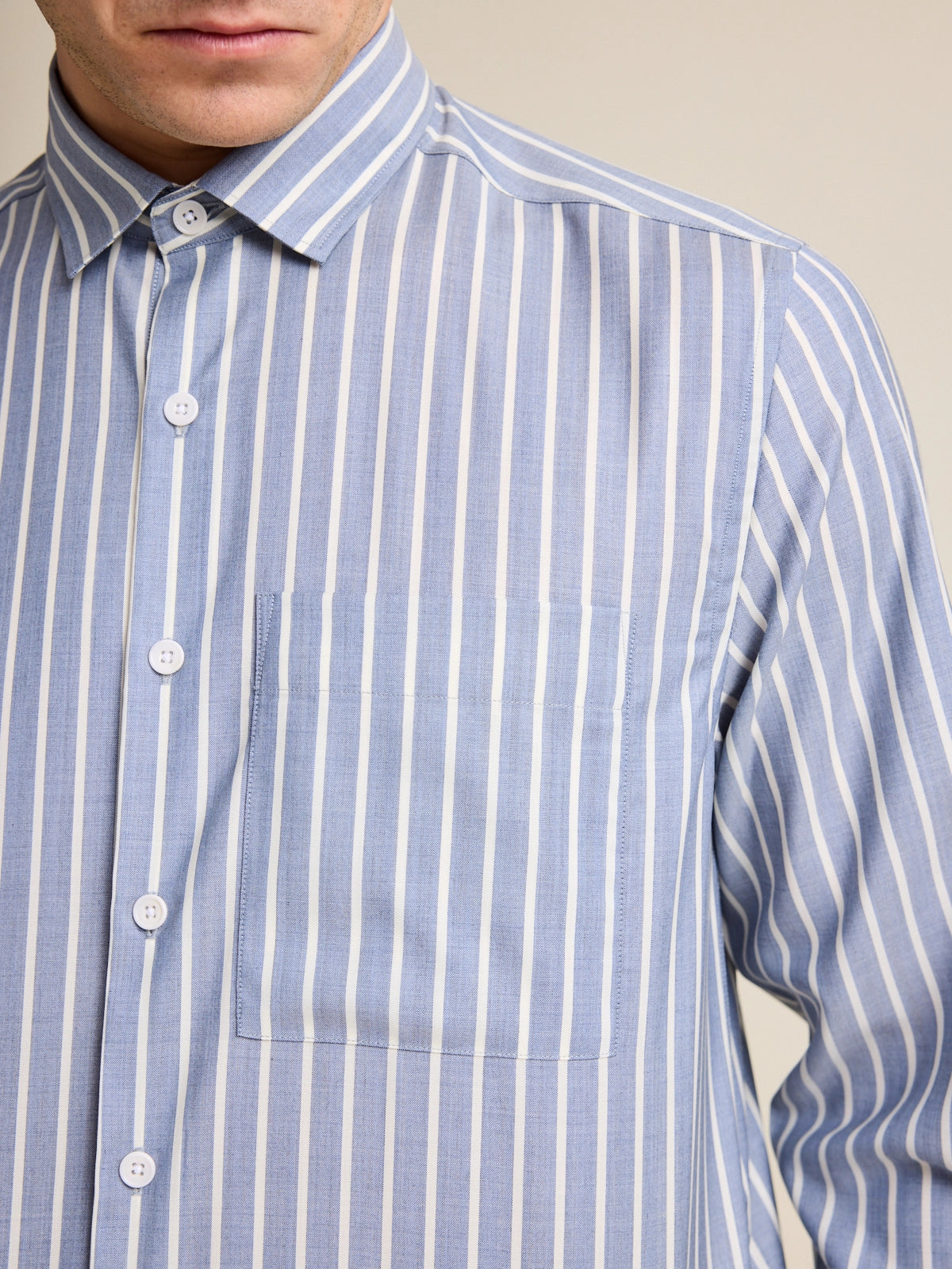 Detail of the chest pocket on a merino wool shirt for men. The merino wool shirt has a striped pattern in navy and white stripe.