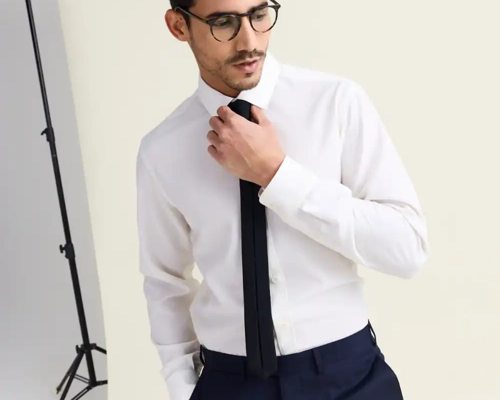 Man wearing a white merino wool shirt with black tie on navy trousers