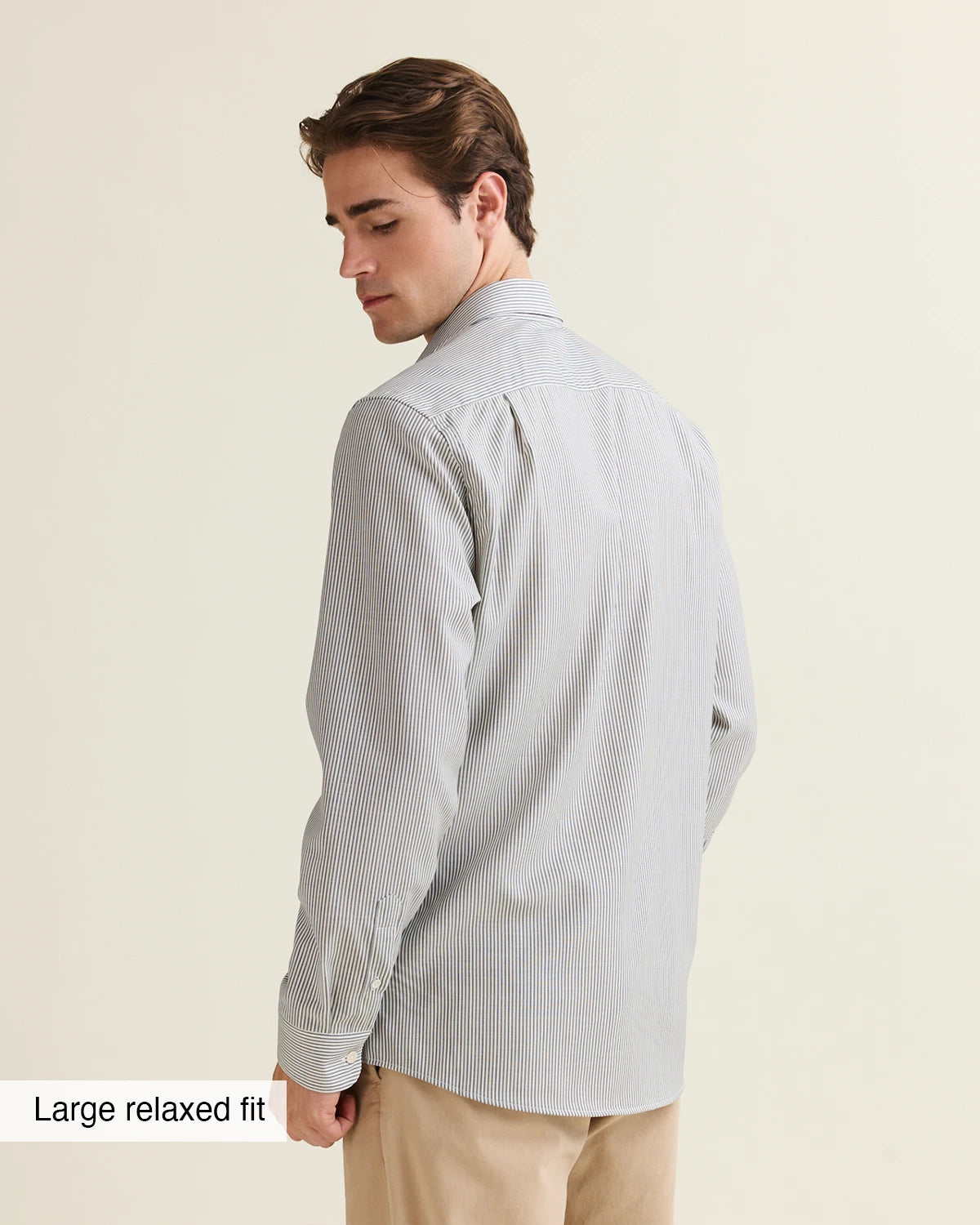 Man wearing a navy bengal striped shirt on a beige pants, view from the back