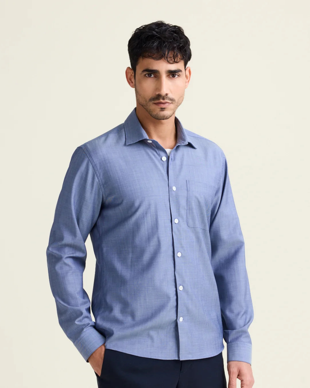 Man wearing a light blue denim merino wool shirt against a beige background
