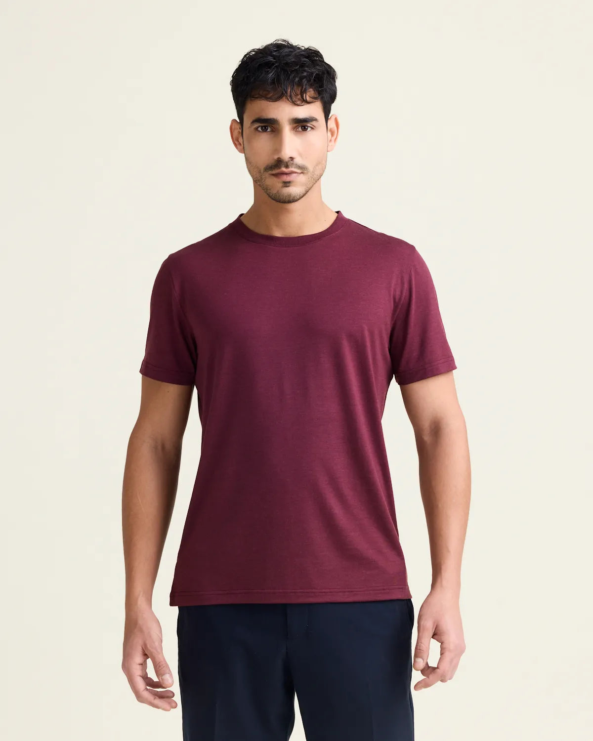 Man wearing a burgundy merinowool t-shirt against a beige background