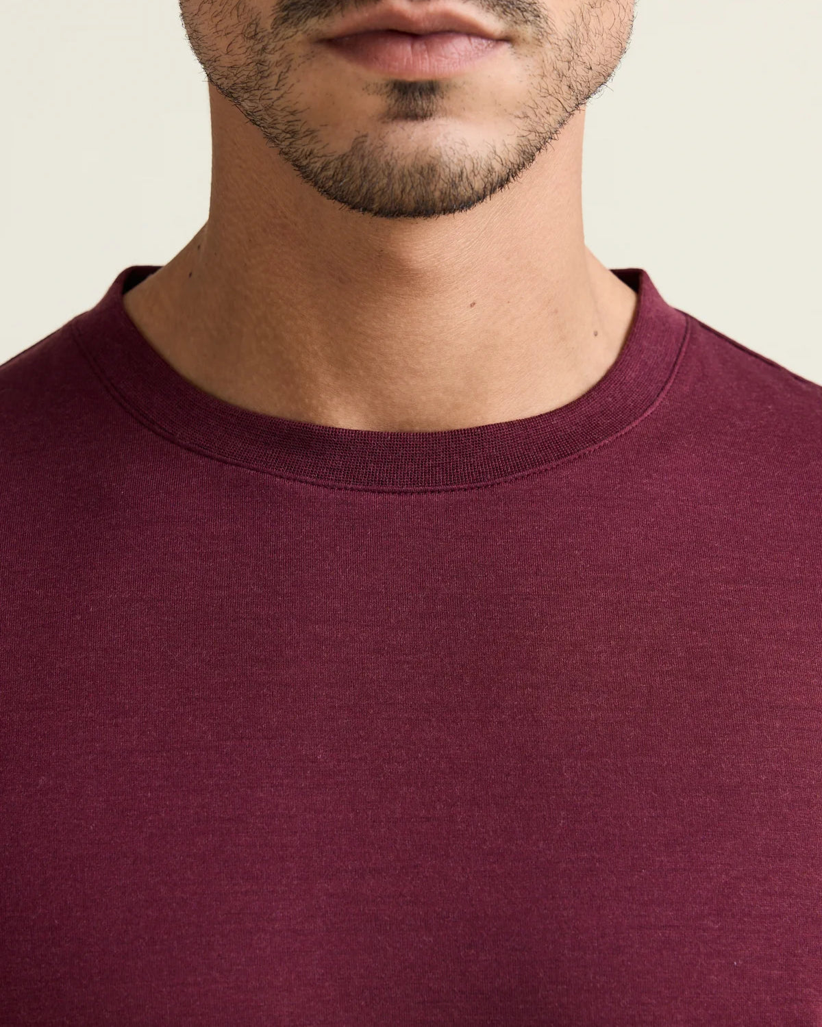 Close up of the crew-neck collar from a men’s merino wool T-shirt in burgundy from the brand Wolk.