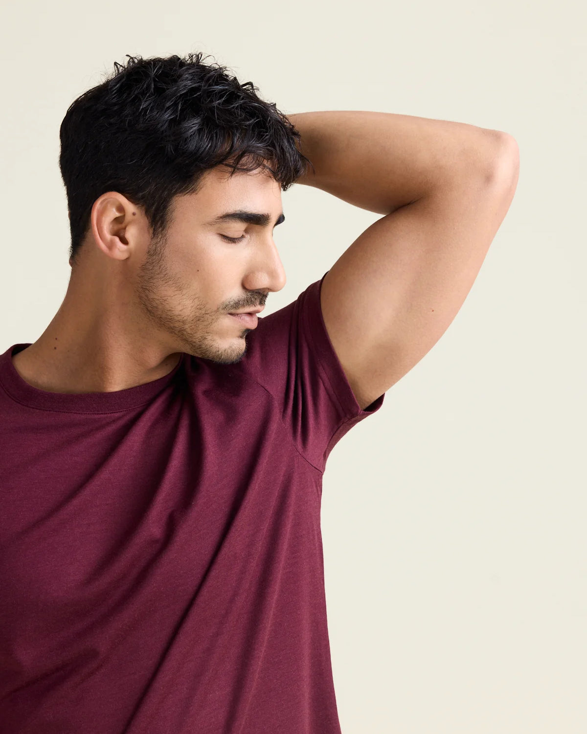Model smells his armpits wearing a merino wool T-shirt with short sleeves in burgundy color with crew neck from Wolk