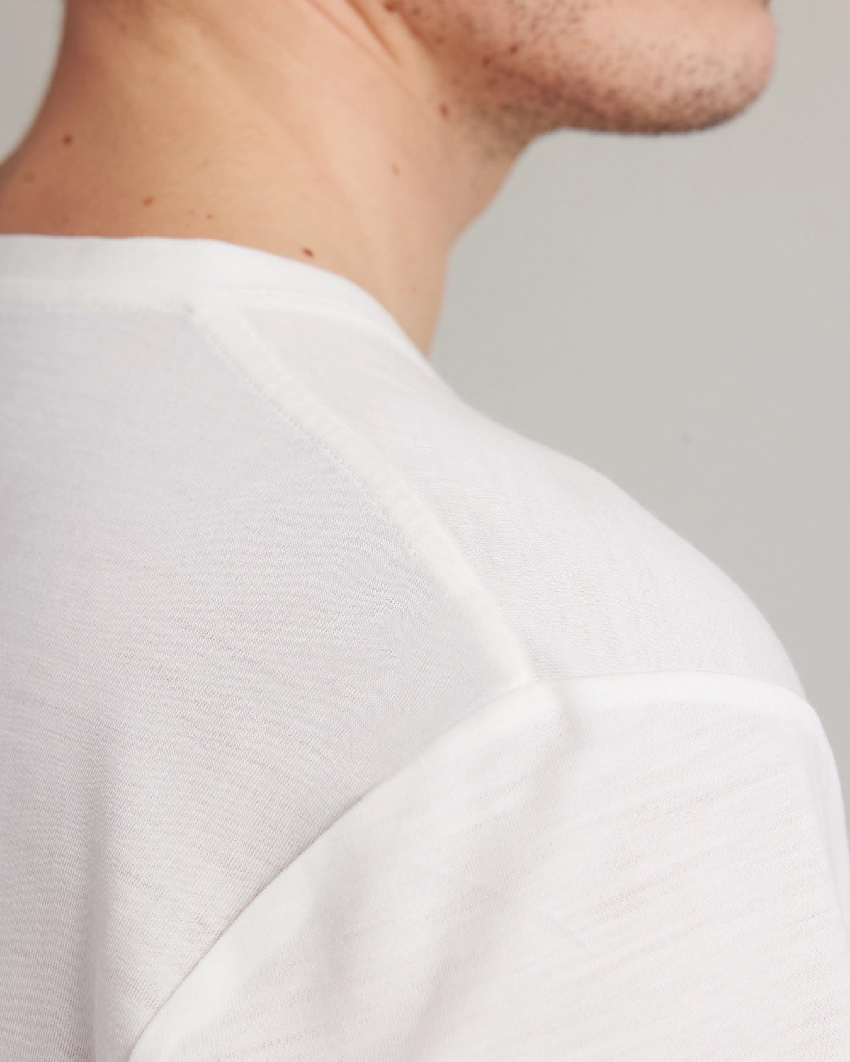 Close-up of a person wearing a white shirt against a neutral background