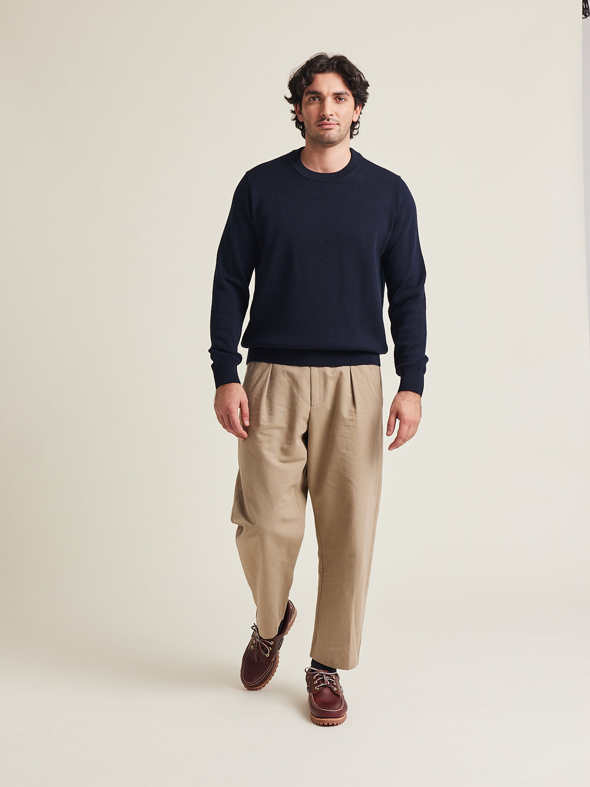 Man wears a merino wool sweater in dark navy color on a beige trousers