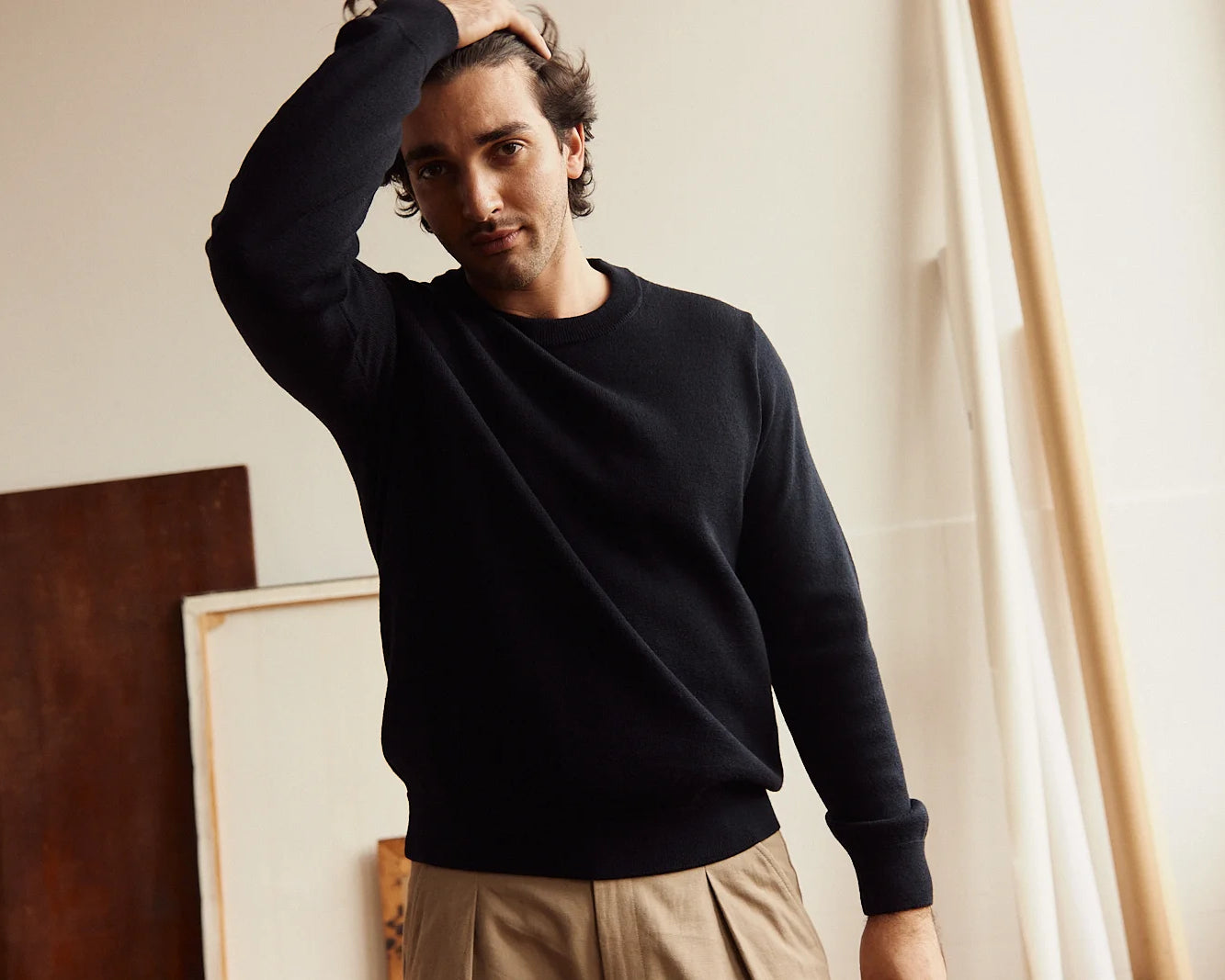 Man wearing a dark navy merino wool sweater and beige pants in an indoor setting