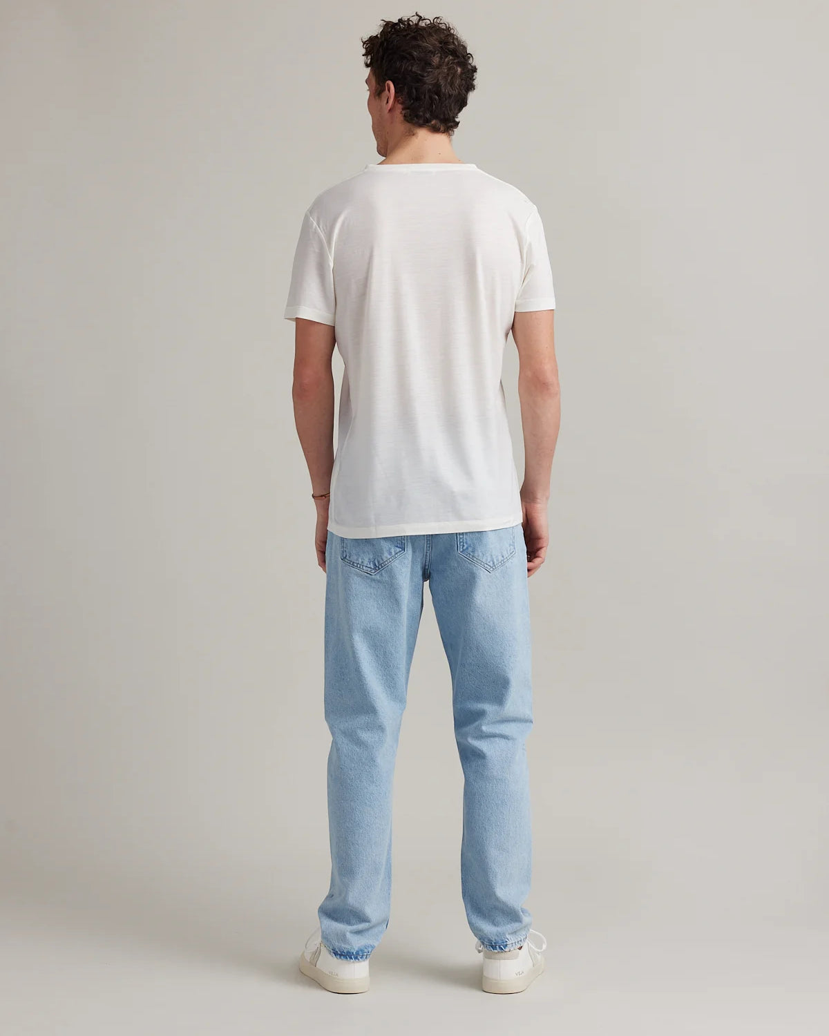 Backside view of model wearing a White merino T-shirt in studio