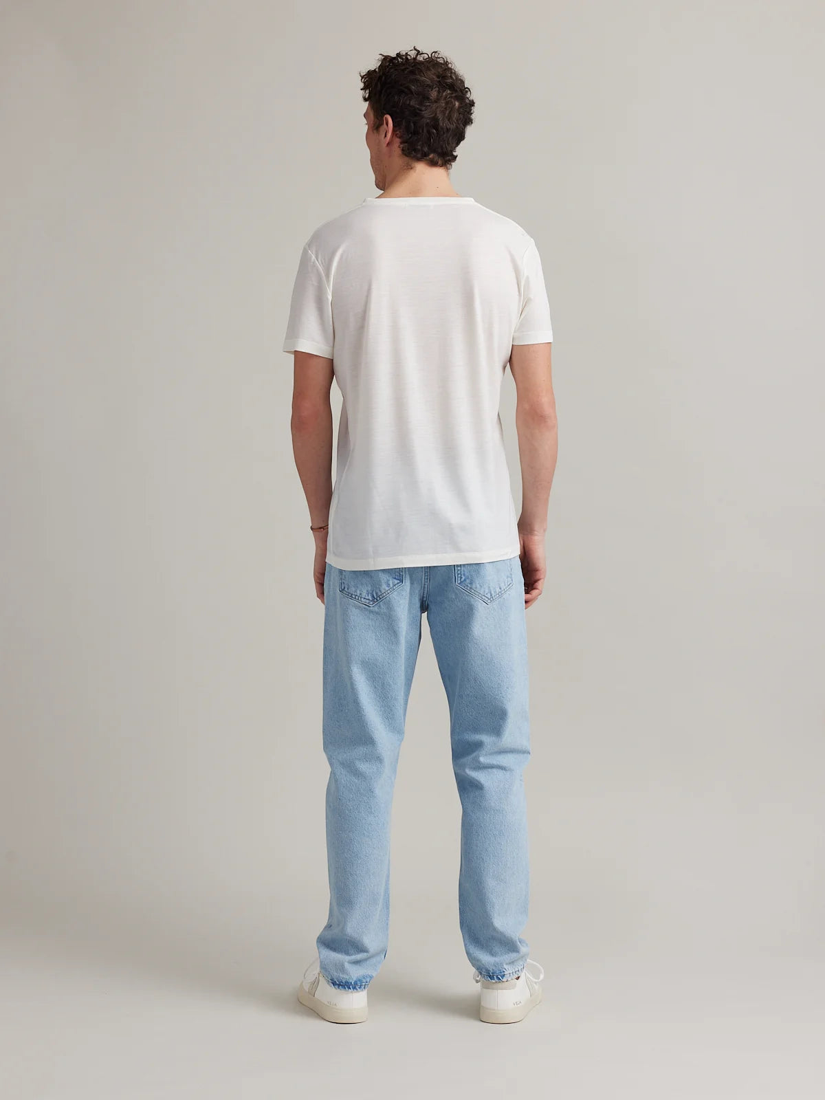 Backside view of model wearing a White merino T-shirt in studio