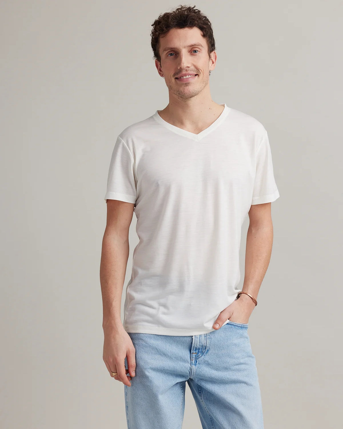 Man wears a white merino wool and nylon blend T-shirt with Vneck and short sleeves from Wolk