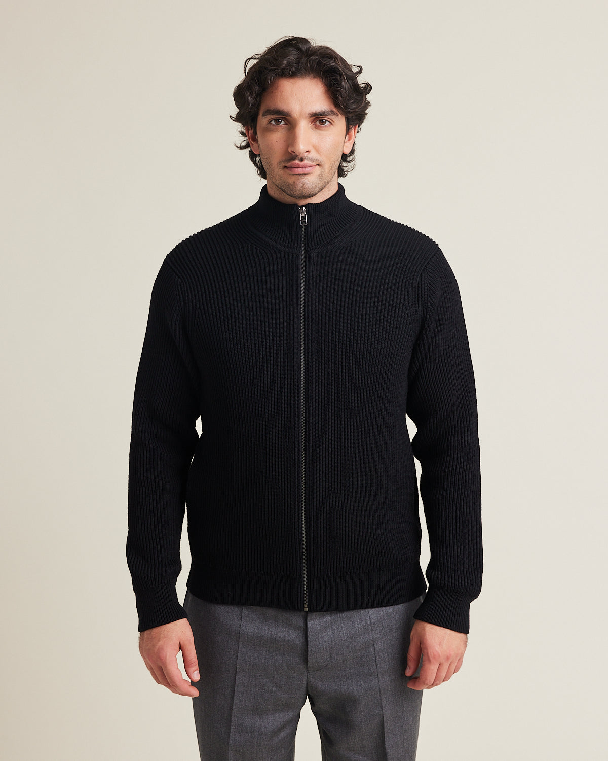 men wears a 100% merino wool knit vest in half cardigan knit with high collar in black color made in heavy weight superfine responsible merino wool