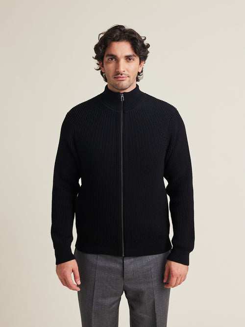 men wears a 100% merino wool knit vest in half cardigan knit with high collar in black color made in heavy weight superfine responsible merino wool