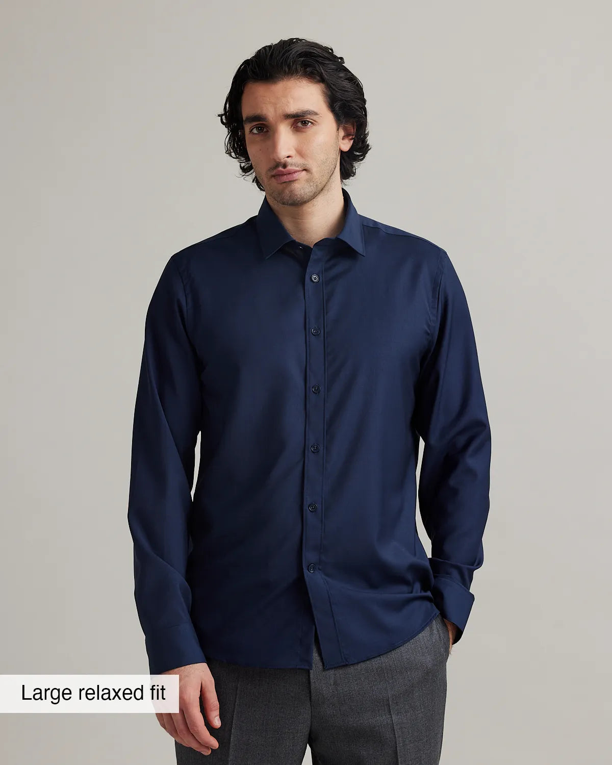 Man wearing a navy blue merino shirt with a large relaxed fit label at the bottom.