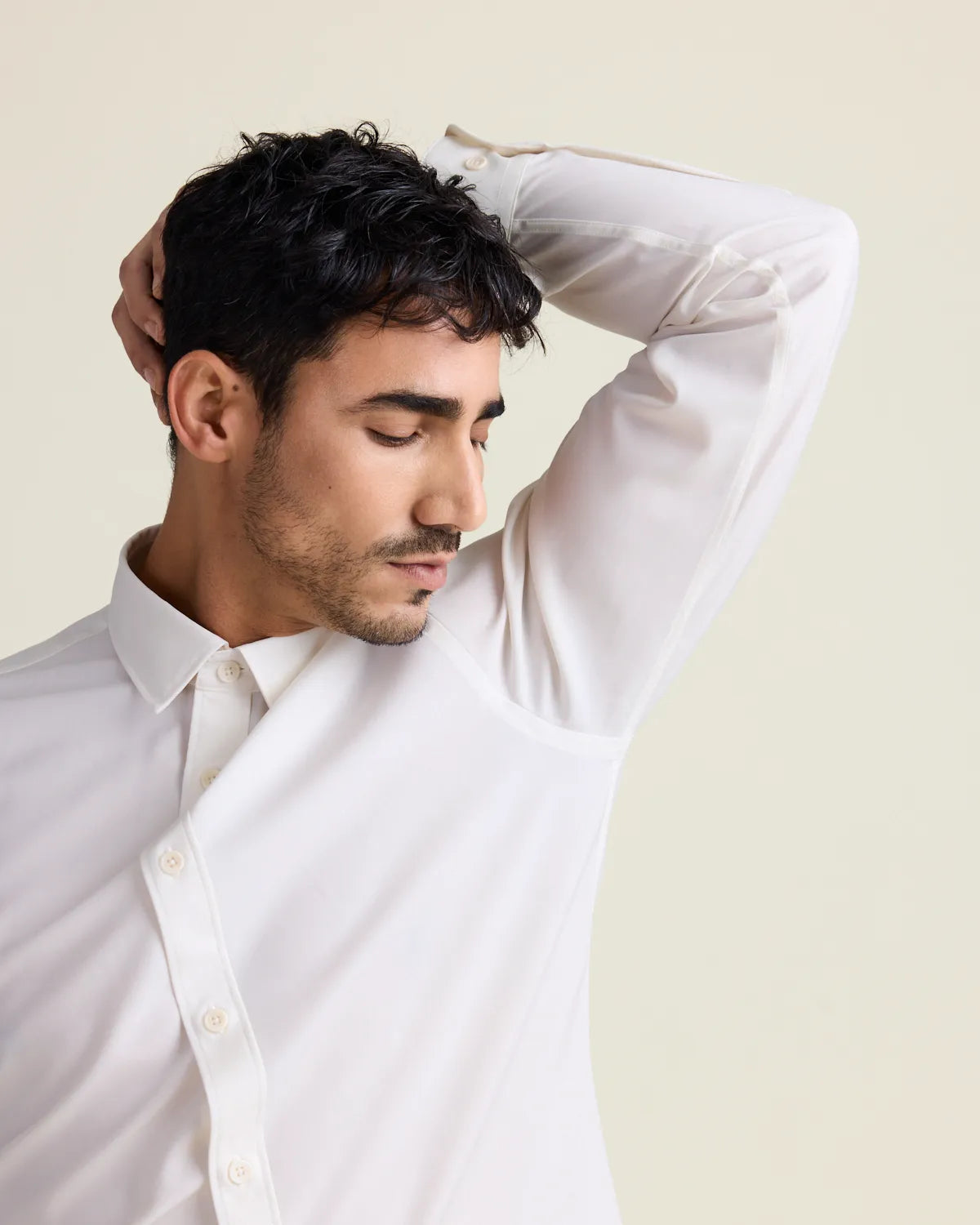 man doing a smell test under his armpit wearing a white merinowool dress shirt