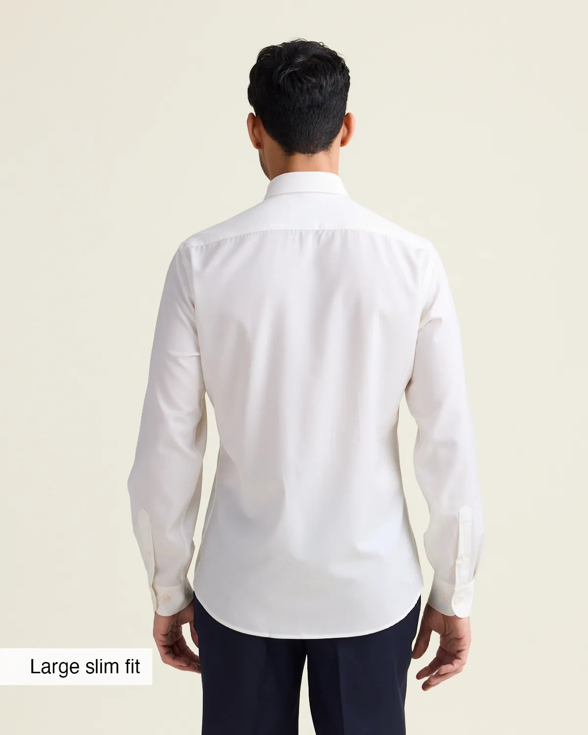 Man wearing a white merino dress shirt with in slim fit showing the untucked back of the shirt