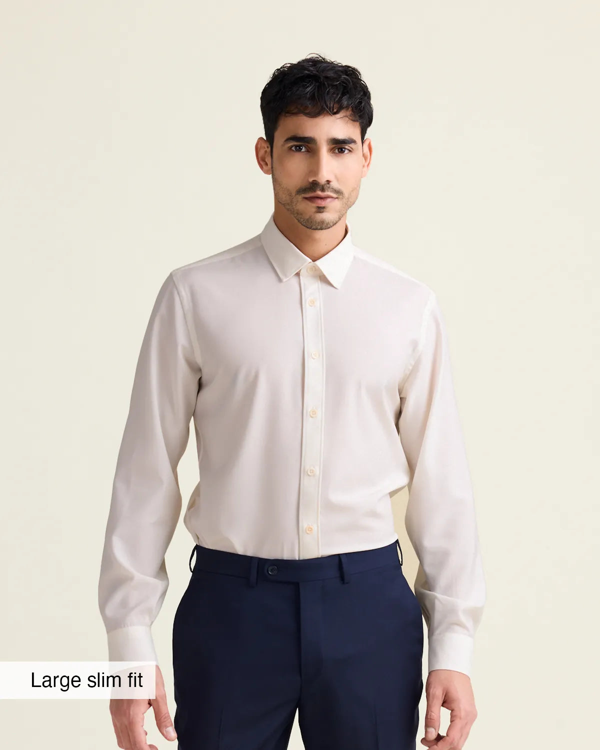 Man wearing a white merinowool dress shirt from Wolk in slim fit with navy trousers on a beige background