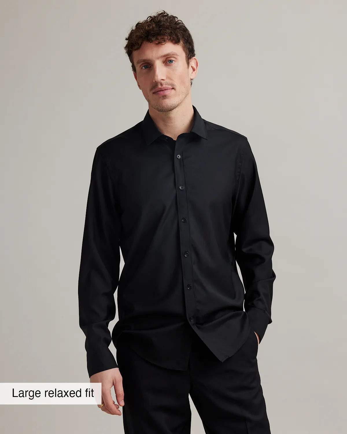 Man wearing a black merino wool shirt with a large relaxed fit on a gray background