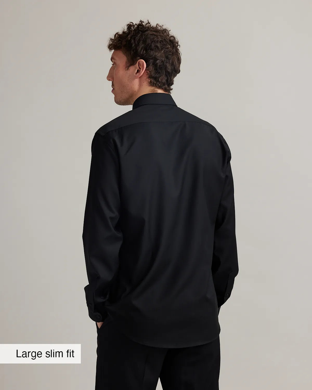 Man wearing a black merino shirt with text 'Large slim fit' on a plain background
