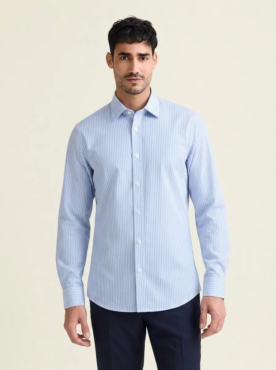 Man wearing a light blue striped merinowool shirt against a beige background