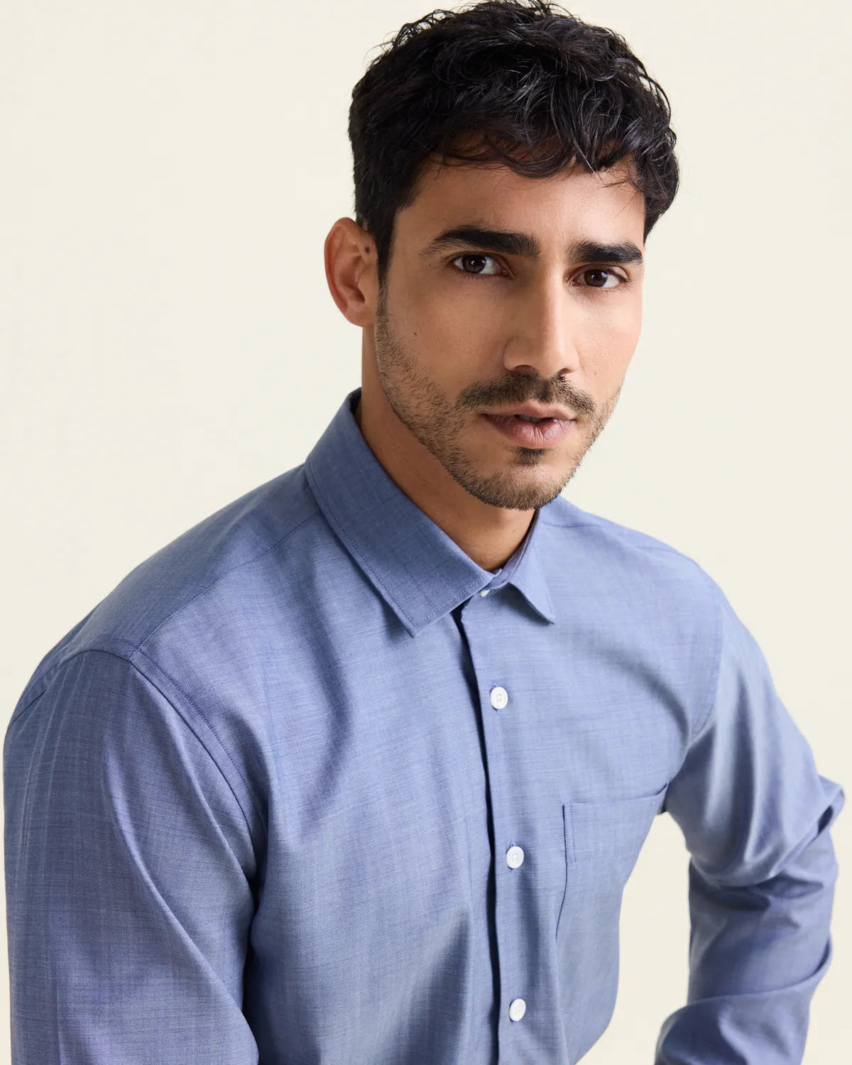 Man wearing a light blue denim merinowool dress shirt against a plain background.