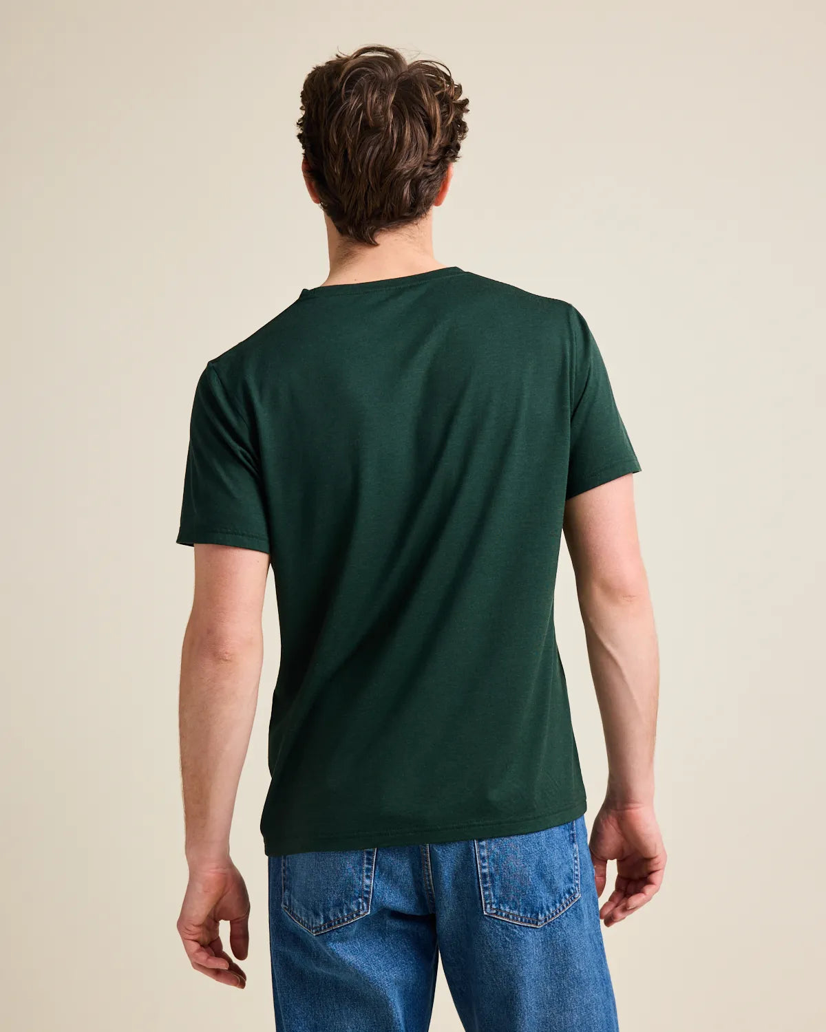 Back view of a person wearing a dark green merinowool T-shirt