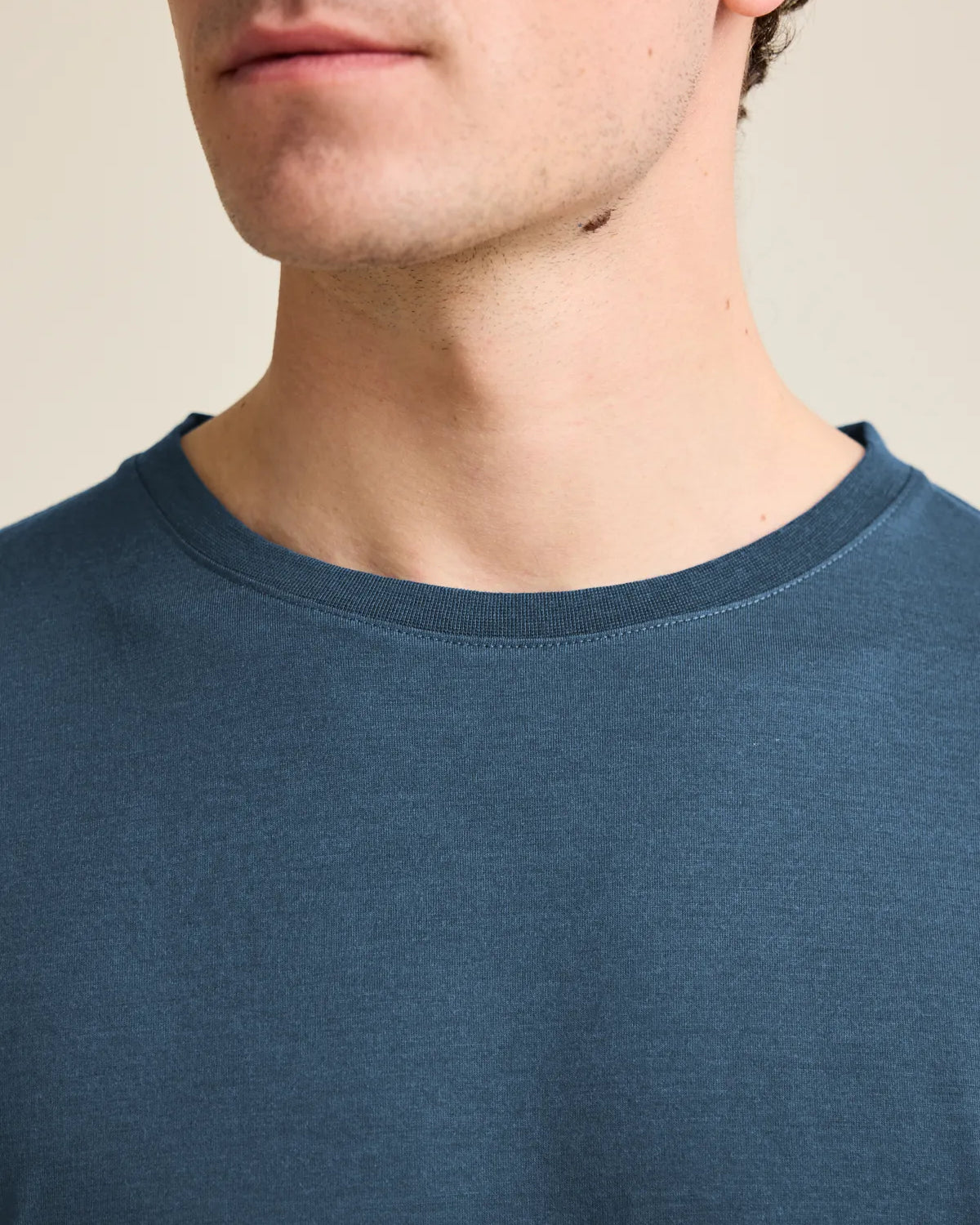 Close-up view of the collar of a denim blue men's merino wool T-shirt by Wolk, showcasing European craftsmanship.