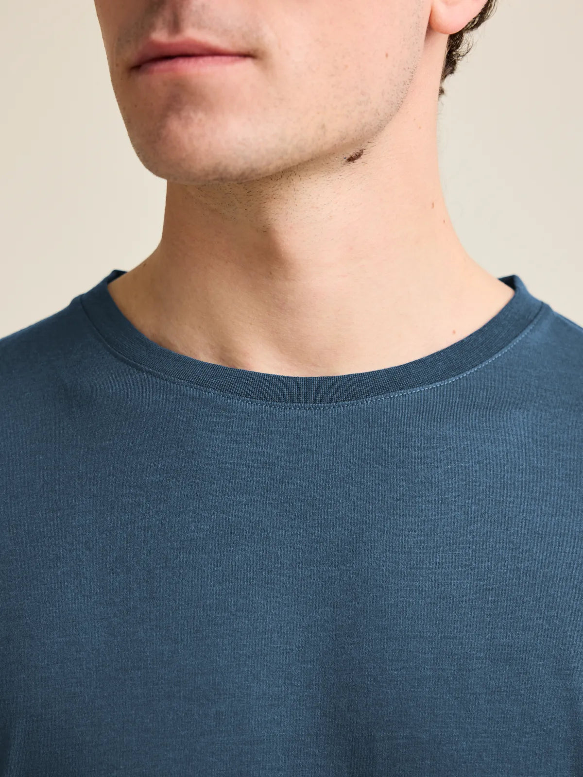 Close-up view of the collar of a denim blue men's merino wool T-shirt by Wolk, showcasing European craftsmanship.