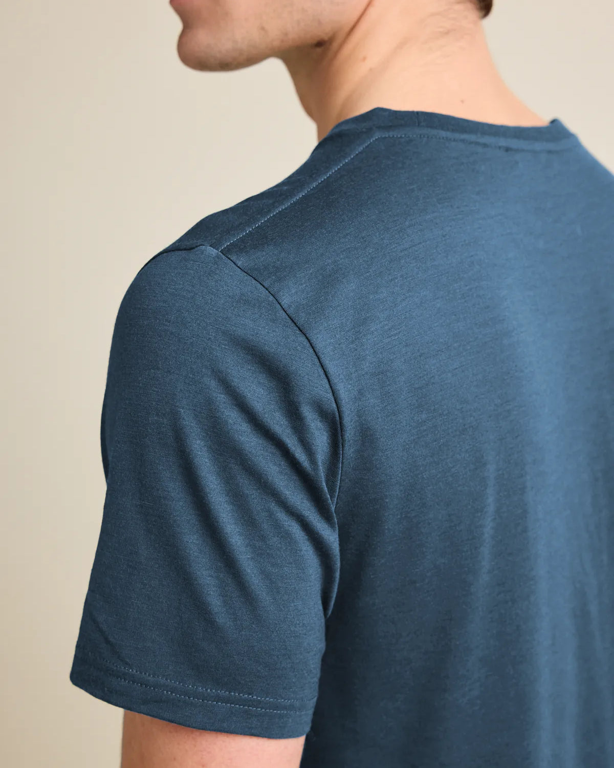 Shoulder detail of a men's denim blue merino wool T-shirt from Wolk, emphasizing fine stitching and quality.