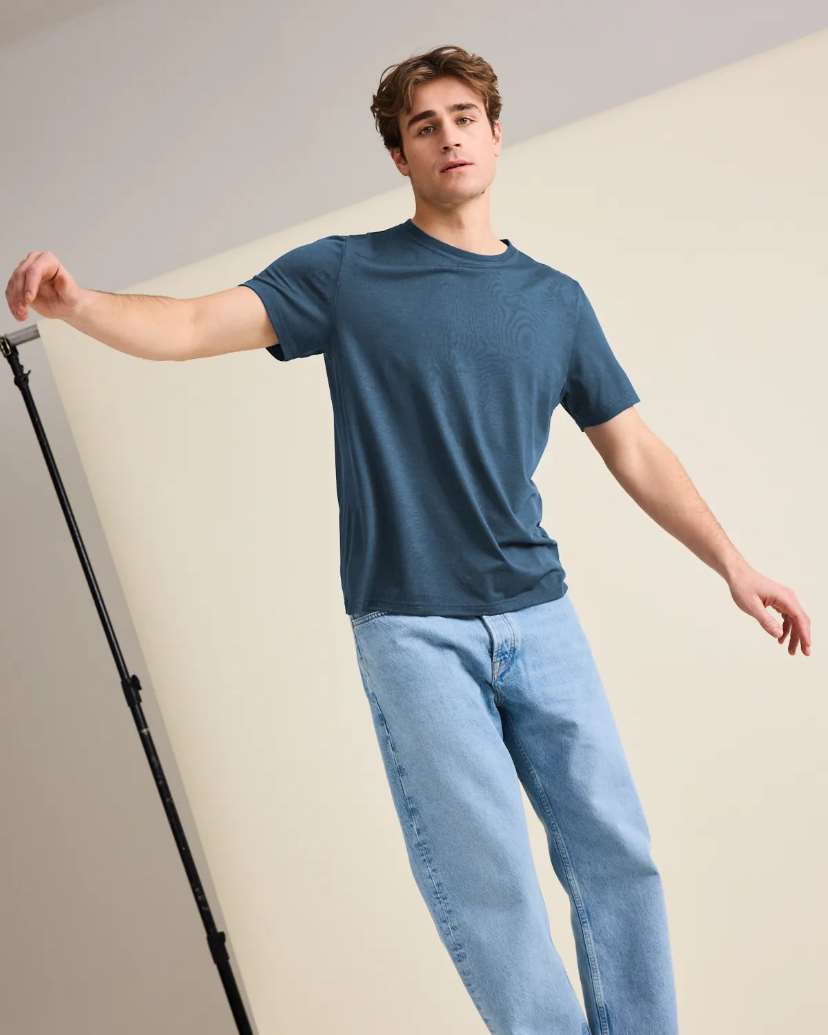 European-crafted, denim blue merino wool T-shirt for men worn by a male model balancing in the studio.